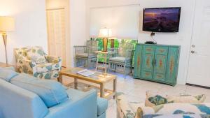 a living room with a couch and chairs and a tv at Stylish Beachside Retreat on Sanibel Island in Sanibel