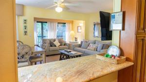 サニベルにあるEscape to Paradise - Tranquil 3-Bedroom Retreat with Wrap-Around Lanai and Private Beachのソファとテーブルのあるキッチンとリビングルーム