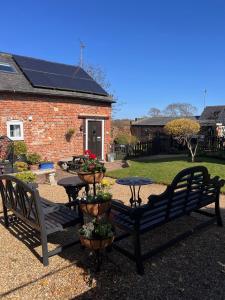 a patio with two benches and a table with flowers at Hunston Mill Self Catering Dog Stay For Free in Chichester