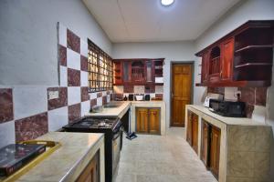 a large kitchen with wooden cabinets and a stove at The Everette Lodge in Sekondi-Takoradi