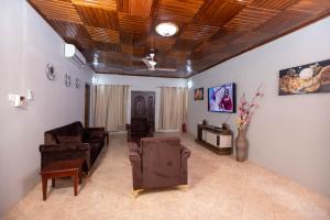 a living room with leather furniture and a wooden ceiling at The Everette Lodge in Sekondi-Takoradi