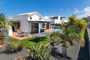a house with a pool and a yard with palm trees at Villa Ambar Cherry in Playa Blanca