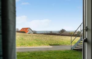 a view from a window of a field with a house at Gudhjem Søpark Lejl 19 in Gudhjem