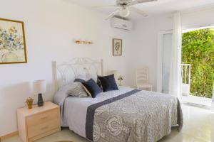 une chambre blanche avec un lit et un ventilateur de plafond dans l'établissement Villa Zodiaco Aries, à Son Bou 25 autres photos