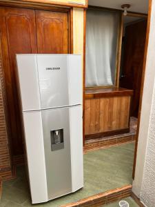ボゴタにあるCasa cerca del CC Titán con seguridad Privadaの窓付きの客室で、白い冷蔵庫が備わります。