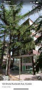 una imagen de un edificio con árboles delante de él en SWEET APARTMENT RUSTABELi, en Kutaisi 5 fotos más