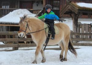 a young child riding on a horse in the snow at Langedrag Naturpark in Tunhovd
