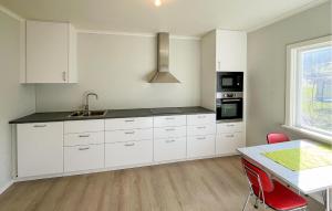 a kitchen with white cabinets and a table with red chairs at 1 Bedroom Nice Apartment In Kvås in Kvås +2 photos