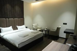 una camera da letto con un letto, una scrivania e delle sedie di Hotel The Royalista a Bathinda