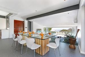 a dining room with a large wooden table and white chairs at Valtameri by Totalstay in Cape Town