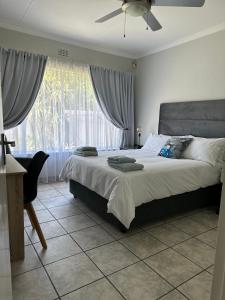 a bedroom with a bed with a fan and a window at AfriSky guest house in Kempton Park