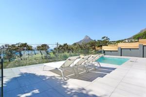 a row of white chairs sitting next to a swimming pool at Valtameri by Totalstay in Cape Town