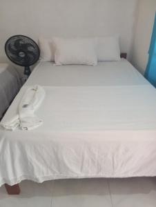 a white bed with a hat and a fan on it at Cordoba Mosquera Esmeralda HOSTAL ESMERALDA in Bahía Solano