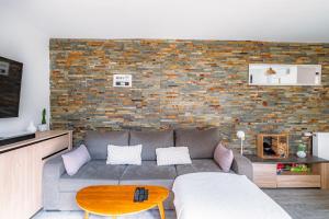 a living room with a couch and a brick wall at La Maison de Sam - Logement entier & Terrasse in Erstein