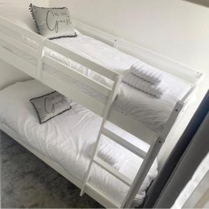 a white bunk bed with white sheets and pillows at Seaside Chalet Mablethorpe in Mablethorpe