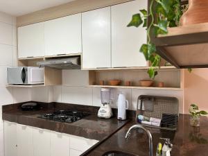 a kitchen with white cabinets and a counter top at Bela Hospedagem - Puerto Ventura, frente mar e ao lado do food park in João Pessoa