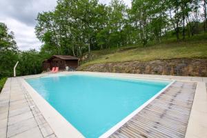 a large blue swimming pool with a house in the background at La grange de gaulejac in Auriac-du-Périgord