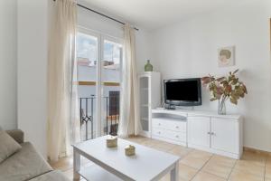 a white living room with a tv and a table at Apartamento Perez Zara 6 in Conil de la Frontera