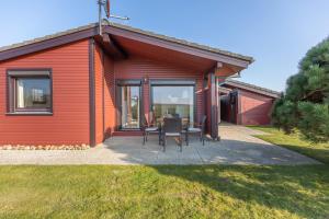 Una casa roja con una mesa y sillas delante de ella. en Deichblick, en Simonsberg