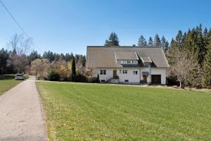 una casa con un gran campo de hierba delante de ella en Ferienwohnung Schartenschmiede, en St. Georgen im Schwarzwald