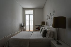 une chambre blanche avec un grand lit et une fenêtre dans l'établissement GuestReady - Charming House Marquês, à Porto