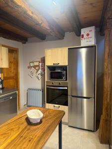 eine Küche mit einem Kühlschrank aus Edelstahl und einem Holztisch in der Unterkunft La Casita de Verdiago in Verdiago