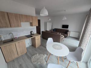 a kitchen and living room with a white table and chairs at Słoneczny Nadmorska in Grzybowo