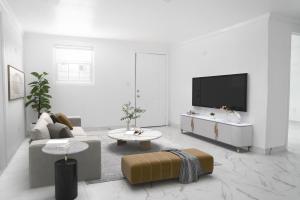 a white living room with a tv and a couch at University Luxe Residences in Tampa
