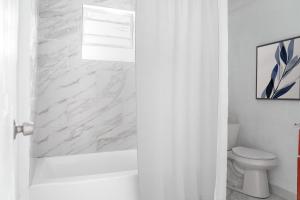 a white bathroom with a tub and a toilet at University Luxe Residences in Tampa