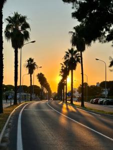 an empty street with palm trees at sunset at Apartamento a pie de playa en El Portil in El Portil
