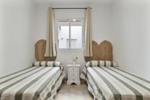 Un dormitorio con dos camas y una ventana. en Apartamento Perez Zara 5, en Conil de la Frontera