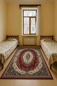 two beds in a room with a rug on the floor at HeyTun Gyumri in Gyumri