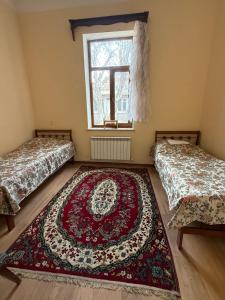 two beds in a room with a rug on the floor at HeyTun Gyumri in Gyumri