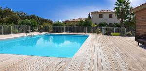 a swimming pool on a wooden deck next to a house at un gout de paradis in Zonza