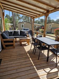 a patio with a couch and a table and chairs at Mobil Home 6 Personnes Camping 5 étoiles Montalivet in Vendays-Montalivet