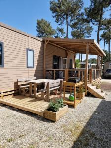 a deck with a picnic table and a gazebo at Mobil Home 6 Personnes Camping 5 étoiles Montalivet in Vendays-Montalivet