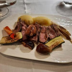 a plate of meat and vegetables on a table at Locanda Gaudemus Boutique Hotel in Sistiana