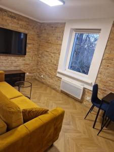 a living room with a yellow couch and a window at Apartament Łęknica in Łęknica