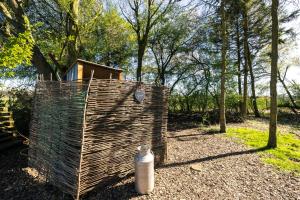 a wooden shed with a water container in the woods at The Warren, Hot Tub and wood burning stove in Brackley +20 photos