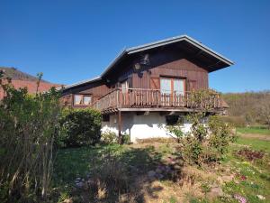 a large wooden house with a deck on a yard at Le Chalet des Masnils in Grosmagny