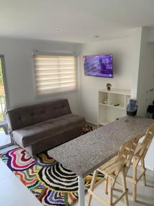 a living room with a table and a couch at Hermoso apartamento con Piscina cerca al Parque Tayrona y Minca in Santa Marta