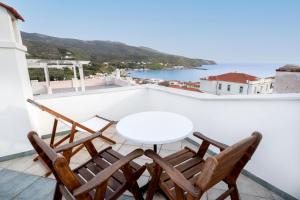a table and chairs on a balcony with a view of the ocean at Archontiko Eleni Hotel in Andros