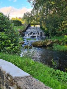 a waterfall in a park next to a river at River View Lodge in Caeathro +7 photos