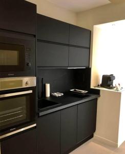a kitchen with black cabinets and a microwave at La Suite Design Dunkerque Plage à 50 mTerrasse Sud in Dunkerque