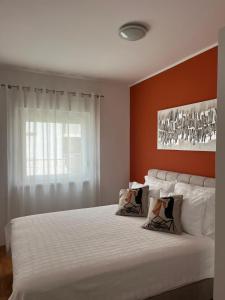 a bedroom with a white bed with an orange wall at Apartment Violetta-Punta in Umag