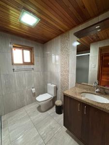 a bathroom with a toilet and a sink and a window at Aconchego e Tranquilidade in Lages