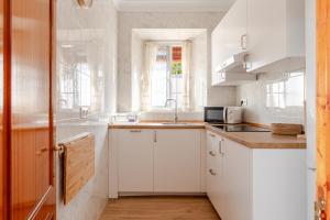 una cucina con mobili bianchi, un lavandino e una finestra di La veleta a Gerena