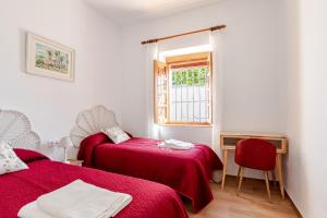2 posti letto in una camera con lenzuola rosse e finestra di La veleta a Gerena Altre 31 foto