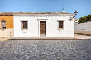 un edificio bianco con una porta su una strada di ciottoli di La veleta a Gerena