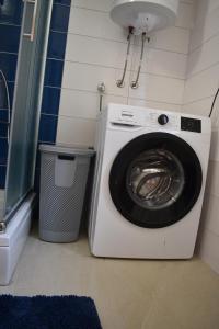 a washing machine in a bathroom with a trash can at Nomand in Preko